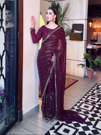 Woman in a maroon saree standing in a modern interior setting