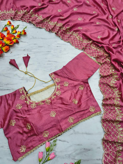 Pink blouse with gold embroidery on a marble surface with flowers.