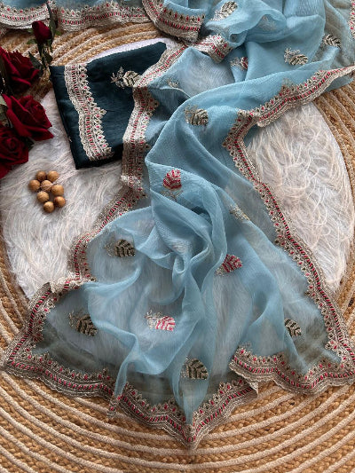 Light blue embroidered fabric on a textured surface with flowers and nuts.