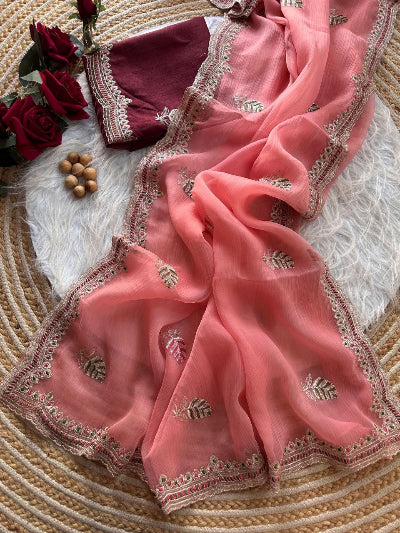 Pink saree with intricate embroidery on a textured surface