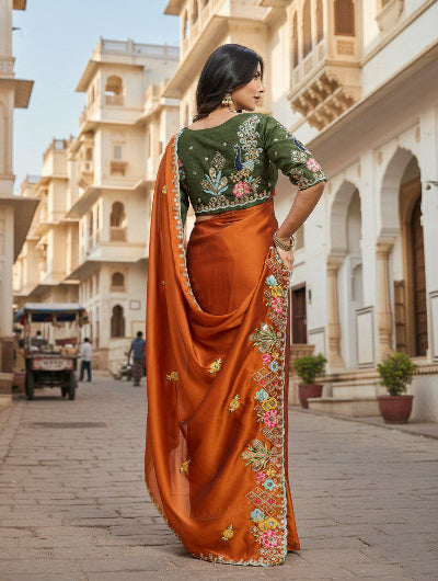 Woman in traditional orange saree with floral patterns in green blouse