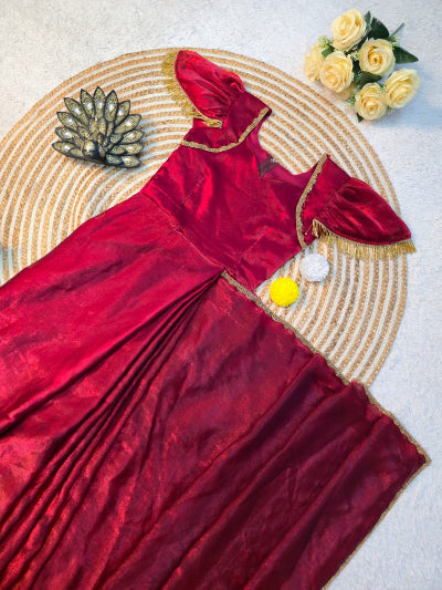 Red saree with gold border on a textured surface with decorative elements.