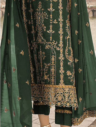 Woman in a green embroidered traditional outfit standing in an architectural setting.