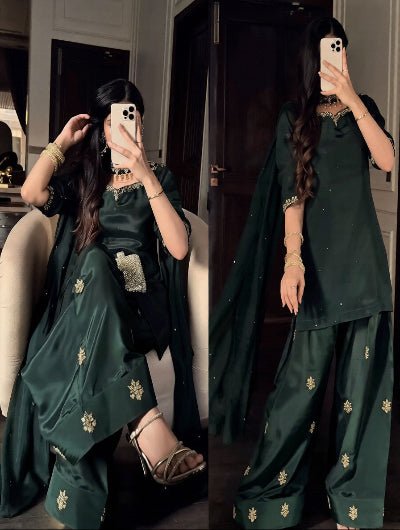Woman in a green traditional outfit with gold details taking a mirror selfie.