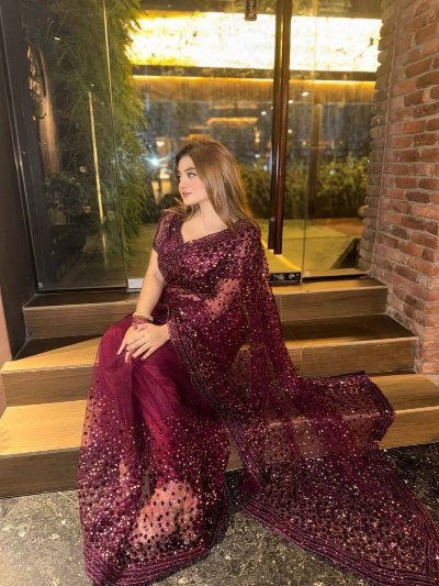 Woman in a purple saree sitting on steps outdoors at night.