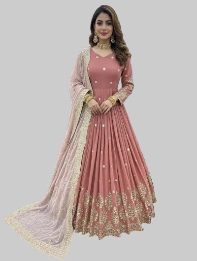 Woman in a pink traditional outfit with gold embroidery in an indoor setting.